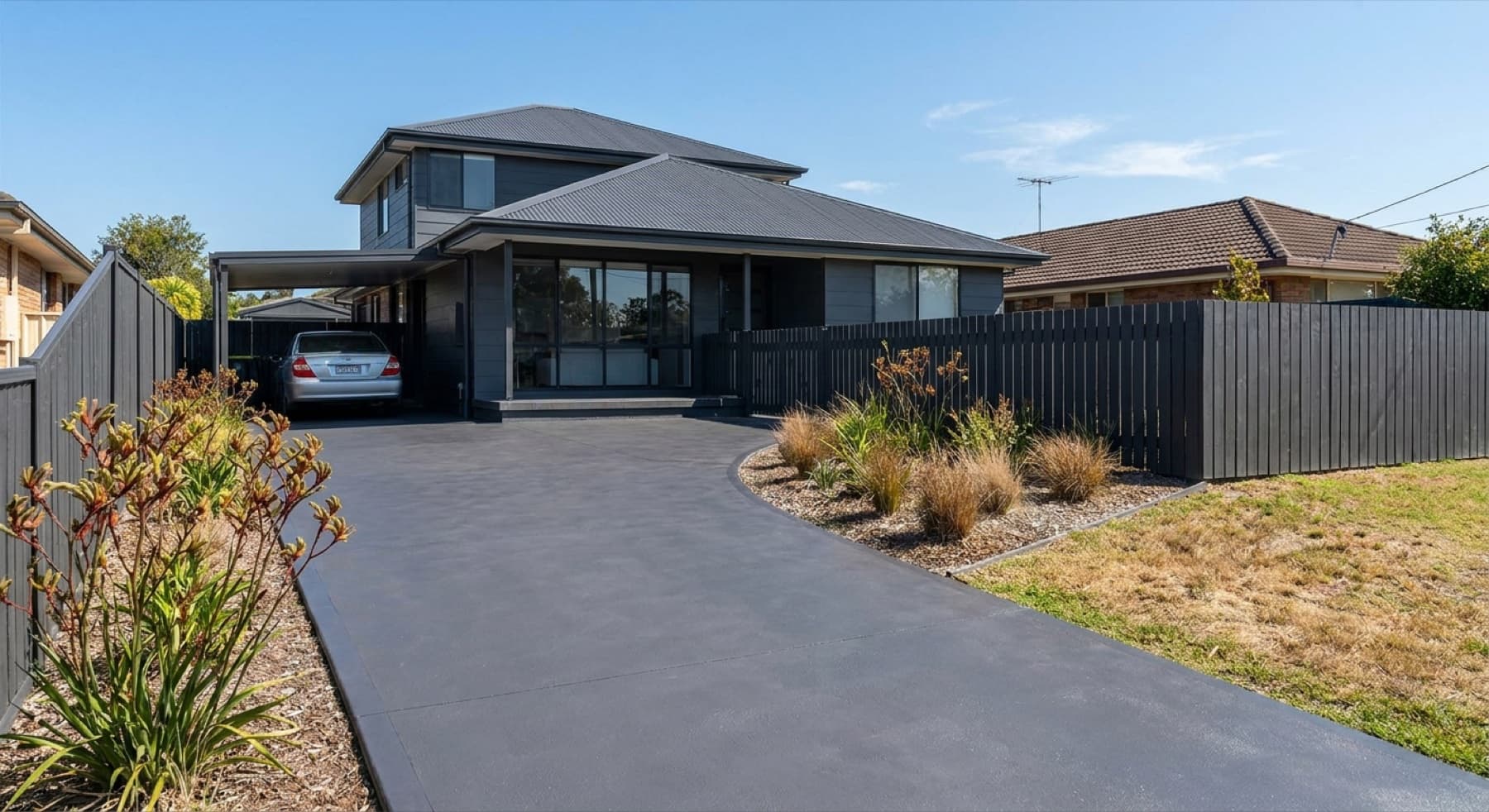 A charcoal colour-sealed driveway matched to a home's dark Colorbond roof and fence