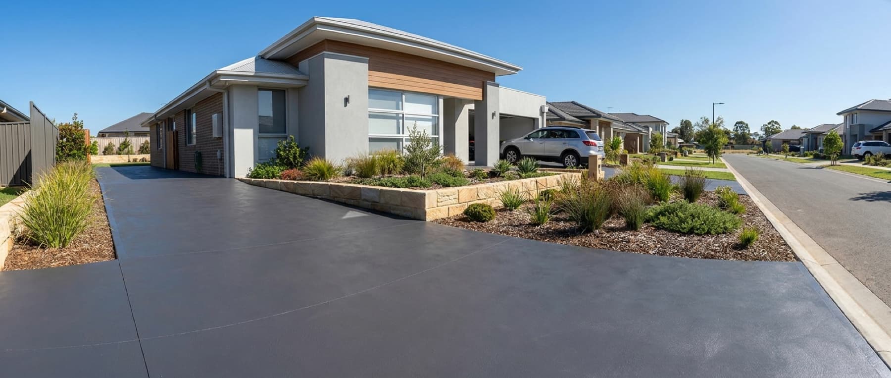 A freshly colour-sealed charcoal concrete driveway at a Central Coast home