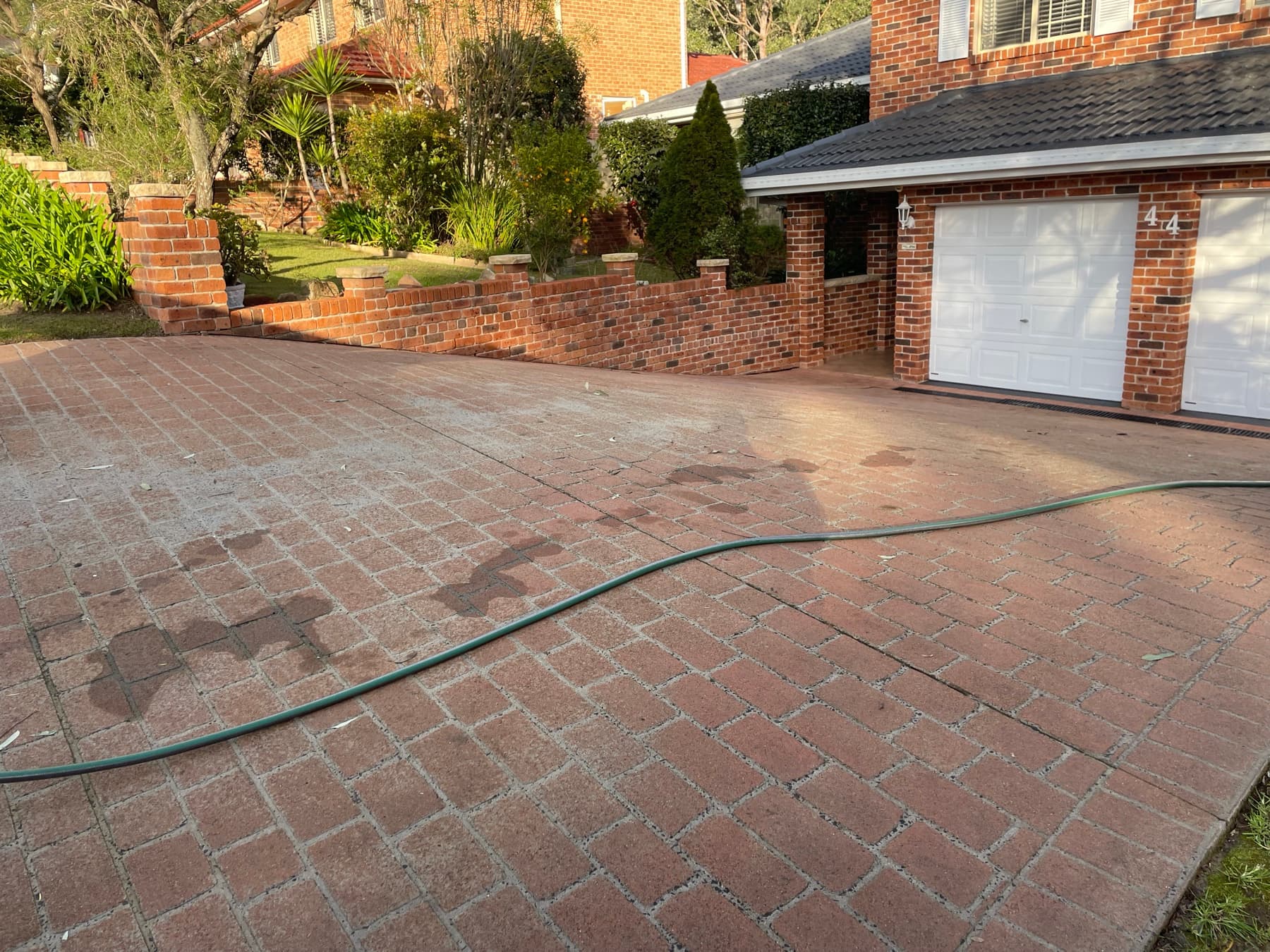 A faded, worn red stencil concrete driveway due for restoration